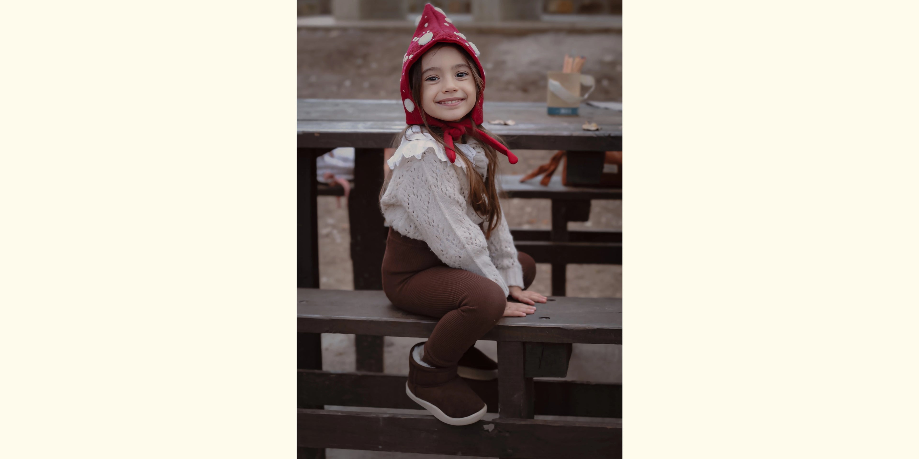 Bambina sorridente seduta su una panchina, indossa stivaletti invernali BabyLab marroni, caldi e confortevoli per l'inverno