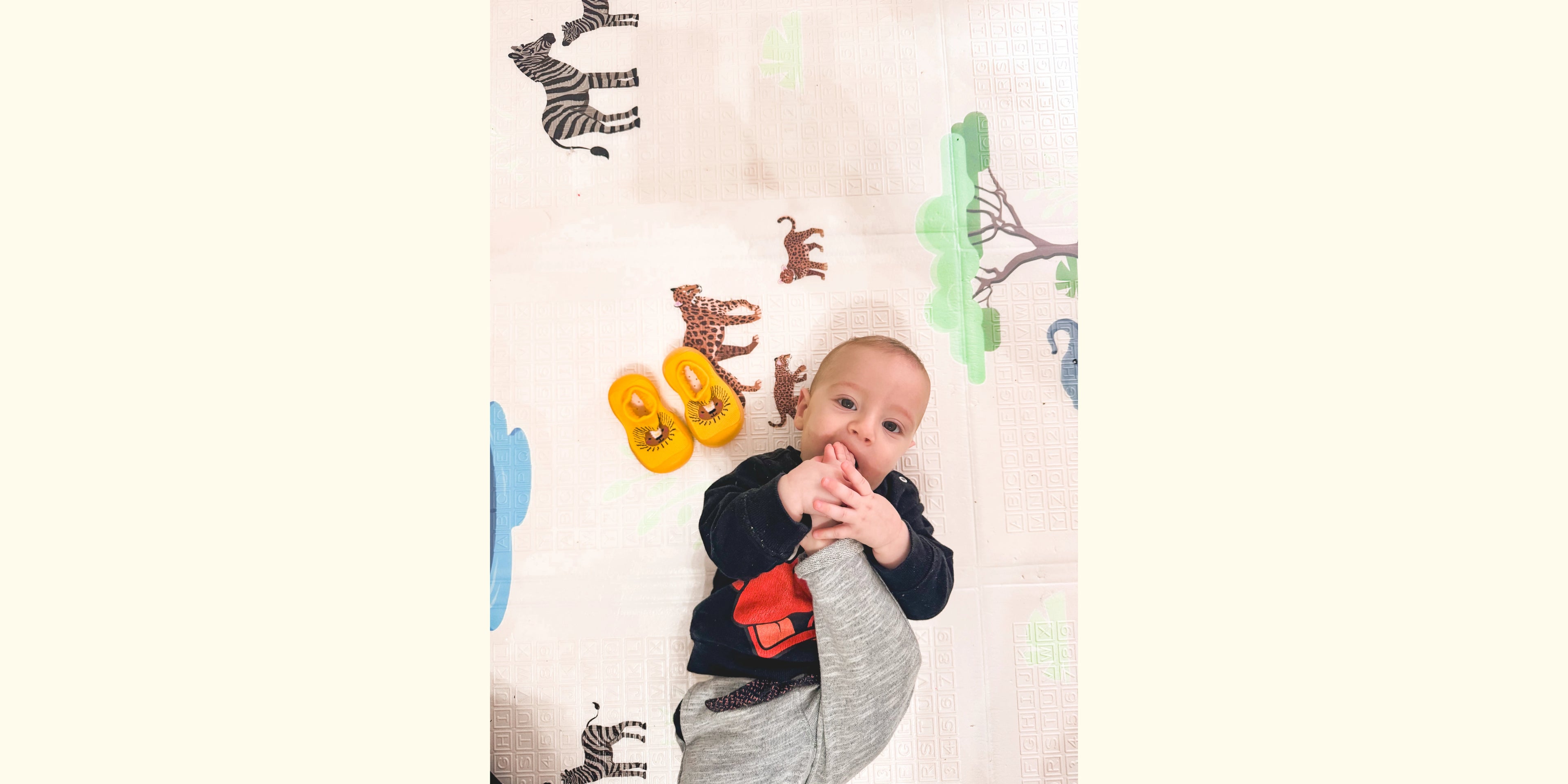 bambino steso con scarpine babylab zoo, sfondo con animali